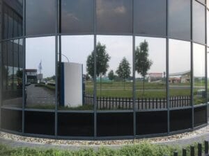 Den Hoorn - Sunblock Stainless Steel 25 gemonteerd op de ramen van een bedrijfsruimte om de overmatige zonnewarmte buiten te houden en de hinderlijke schittering te reduceren